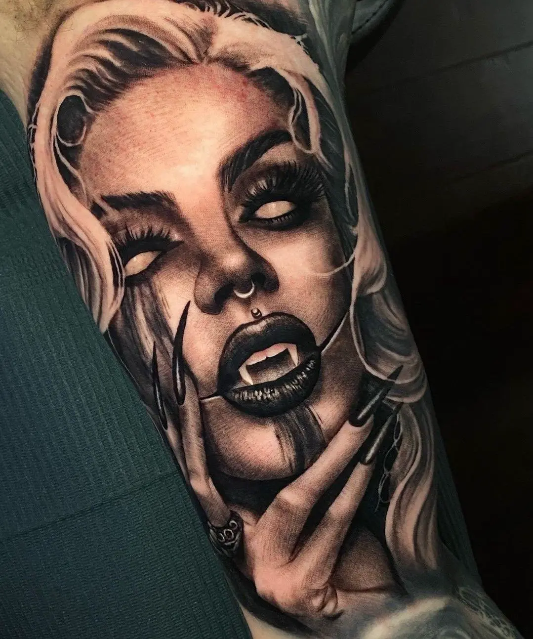 Black and grey realism portrait tattoo of a woman with pale eyes and fangs